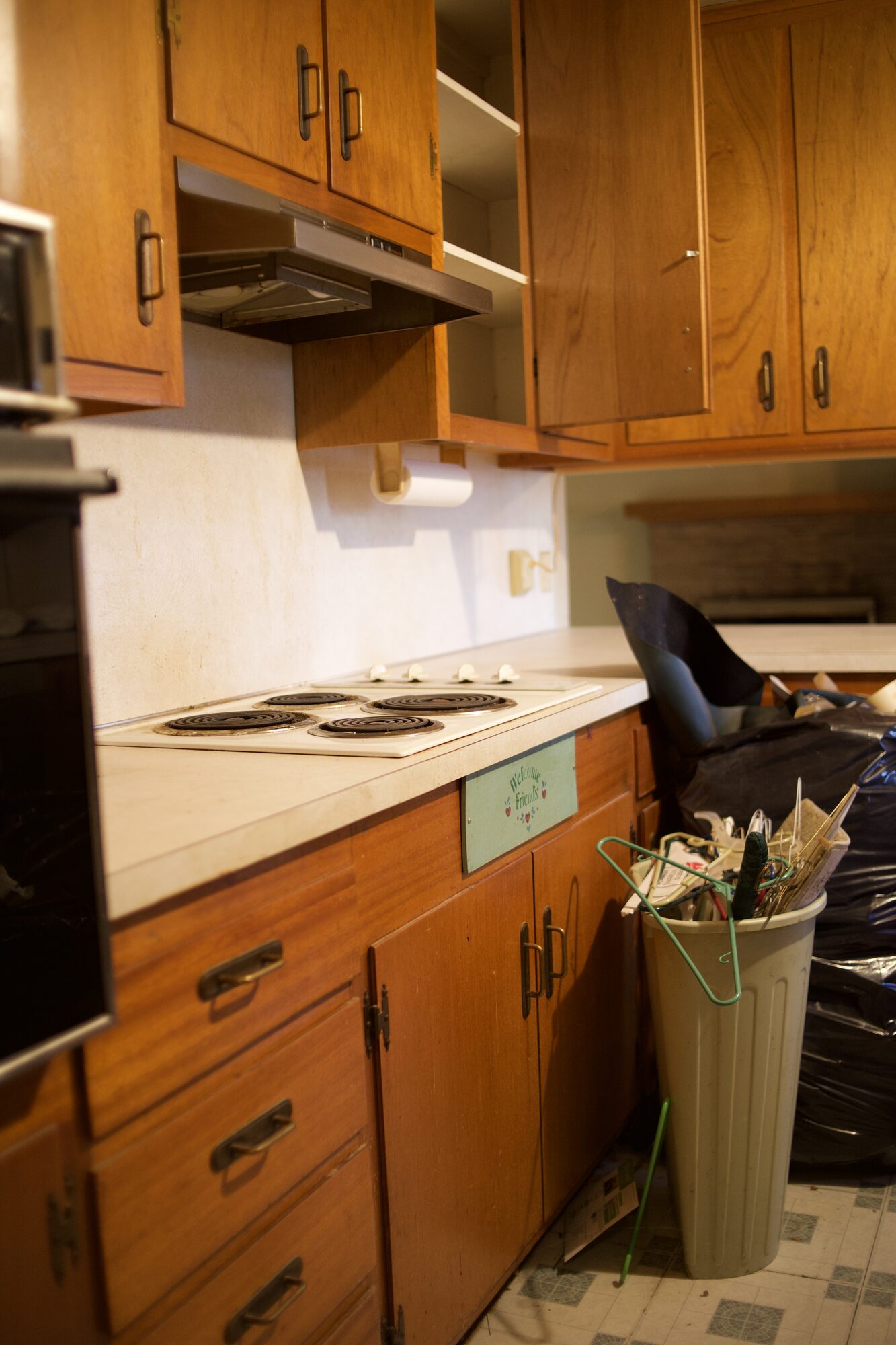 Dated 1970s kitchen with original wood cabinets and a coil cooktop in an inherited Tulsa house